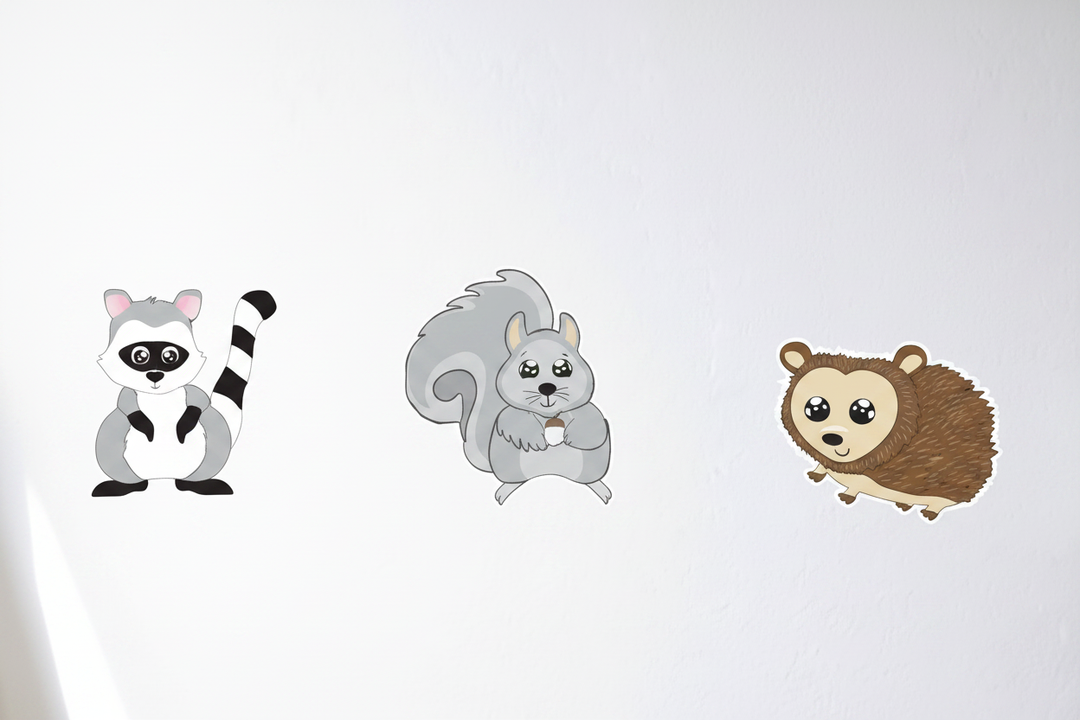 Cute cartoon raccoon squirrel and hedgehog wall decals spread out on white nursery wall — woodland forest animal peel and stick stickers
