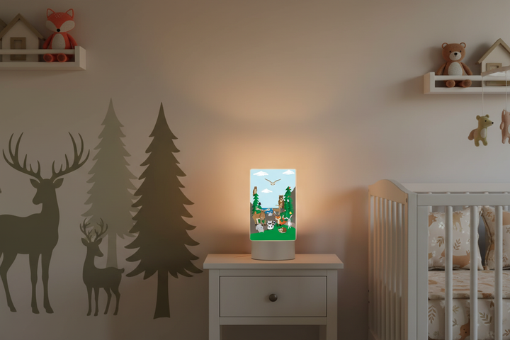 Forest animal night light glowing warmly on white nightstand in styled woodland nursery creating soft magical bedtime atmosphere